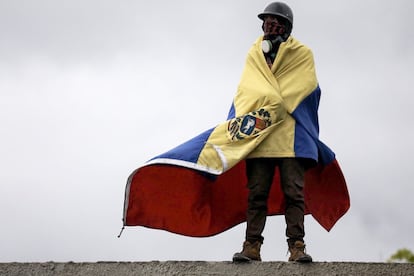 Un hombre que usa máscara de gas envuelve su cuerpo con una bandera venezolana durante una manifestación denominada "Venezuela le da un mensaje a la FAN (Fuerza Armada)", el 24 de junio de 2017, en Caracas.