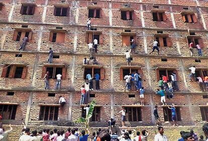 Decenas de indios &quot;trepan&quot; por la pared de un edificio en Hajipur para para ayudar con las respuestas a los estudiantes que realizan un examen en su interior.