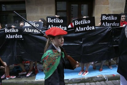 Una mujer, integrante de la compañía Jaizkibel, desfila en Hondarribia mientras otras portan carteles en contra de la participación de las mujeres.