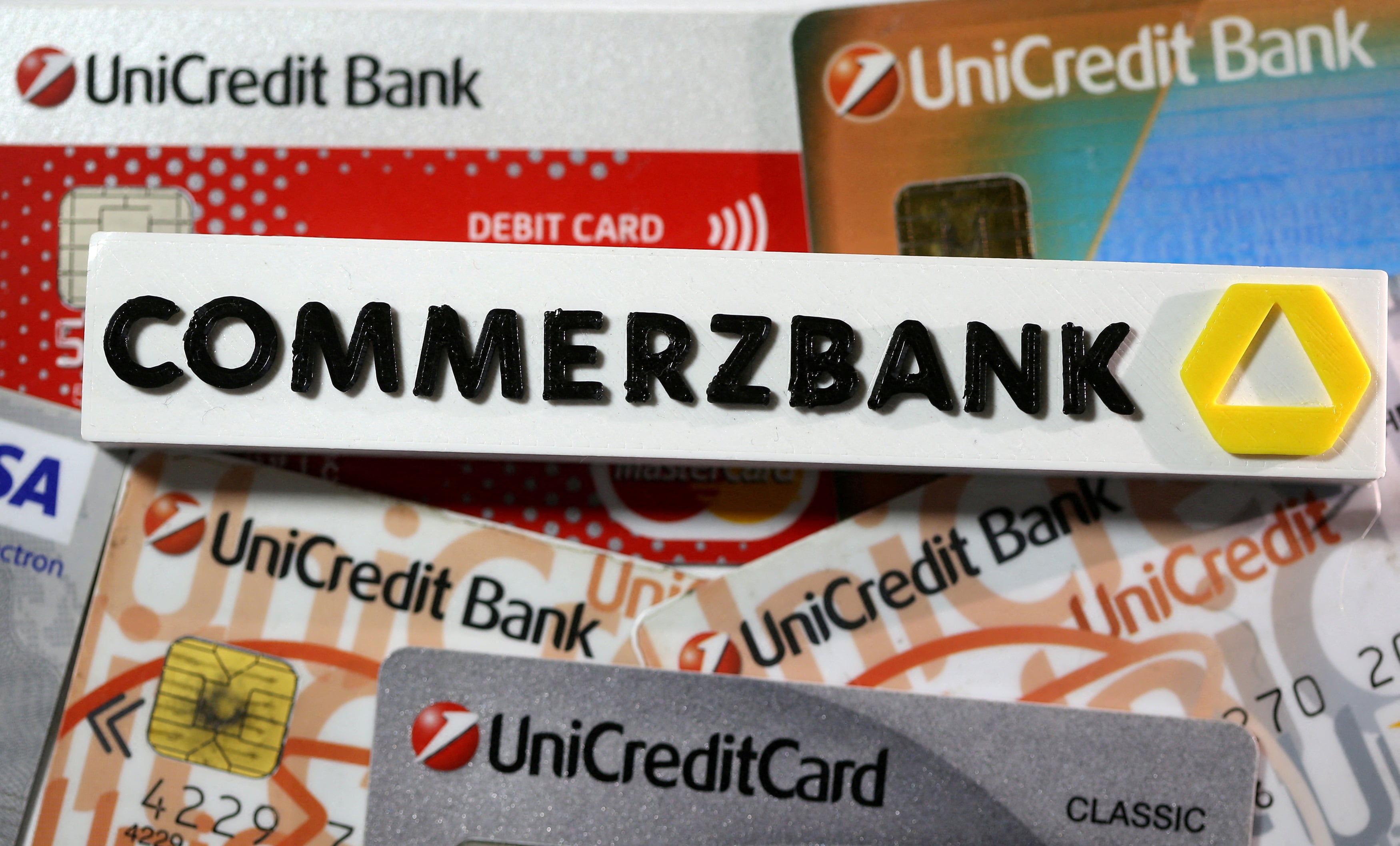 Un logotipo de Commerzbank impreso en 3D cerca de las tarjetas de crédito de Unicredit