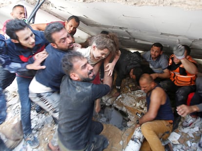 Unos ciudadanos rescataban a una niña de entre los escombros de un edificio derruido, este domingo en la ciudad de Gaza.