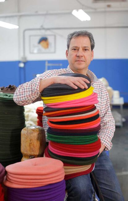 Ander Astigarraga, director comercial de la empresa con una pila de boinas de colores.
