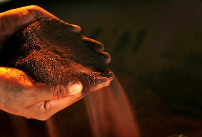 Un trabajador posa con un puñado de mineral de níquel.