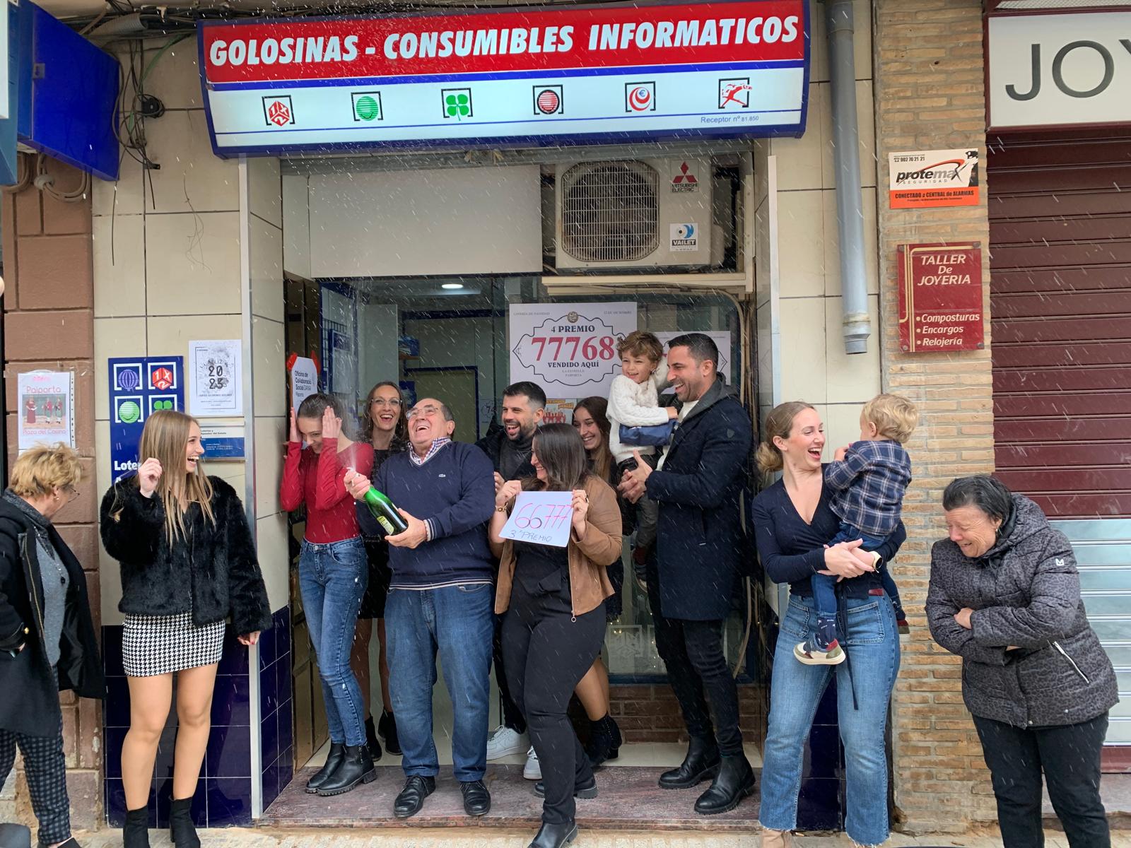 La lotera y su familia celebran el haber vendido el tercer premio de la lotería de El Niño ante su negocio La Estrella.