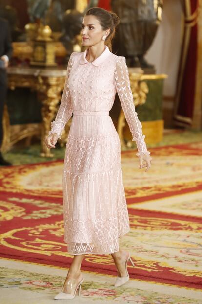 La reina Letizia eligió un conjunto de Felipe Varela, otro de sus diseñadores favoritos, para el Día de la Hispanidad. Se trata de un vestido camisero abotonado y de corte 'midi' en color rosa talco, con cuello bebé y elaborado con seda y tull. Uno de los detalles más llamativos de la prenda son las pequeñas mariposas bordadas, que se aprecían sobre todo en las mangas. Un diseño que recuerda al vestido de Maje que lució en noviembre en Cuba.