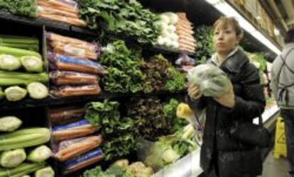 Una mujer compra hortalizas en un supermercado. 