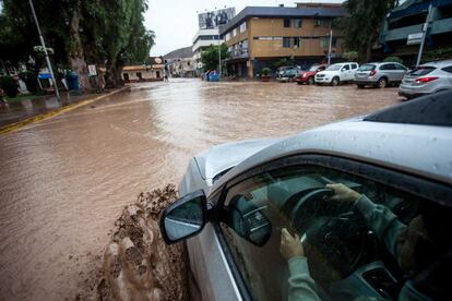 Un coche intenta cruzar una calle inundada por el desborde del río Copiapo en Chile.