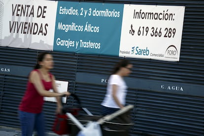 Dos personas pasan ante una promoción de Sareb, en una imagen de archivo.