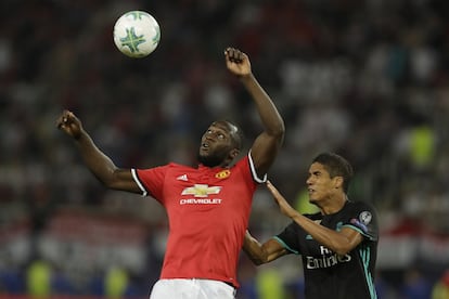 Romelu Lukaku (izquierda), del Manchester United, remata de cabeza ante Raphael Varane del Real Madrid.