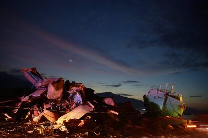 Montones de escombros y un barco varado tras el terremoto y el tsunami de Indonesia, durante el anochecer en Donggala.