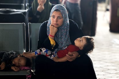 Una mujer junto con su hijo esperan para pasar por la frontera de Rafah con Egipto, al sur de la Franja, este jueves.