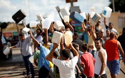 Pessoas fazem fila com galões em frente a um posto de combustíveis em Brasília, onde quase já não há gasolina, etanol e diesel para a população/ 