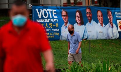 Varias personas pasean ante un cartel del Partido de los Trabajadores, en la oposición, en vísperas de las elecciones generales de Singapur, este viernes.