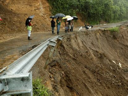 Algumas pessoas olham uma estrada parcialmente destroçada pelas chuvas em Costa Rica.