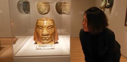 Una mujer observa una cabeza de cerámica vidriada en la exposición de Francisco Durrio. 