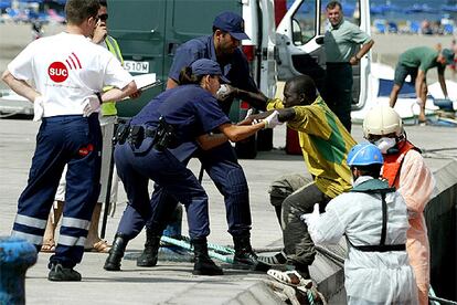 Aunque durante el verano han llegado miles de inmigrantes a Canarias, el fin de semana del 18 de agosto registró la mayor oleada. Sólo el viernes, 512 personas llegaron a distintos puntos de las islas. En la imagen, tomada el viernes en Los Cristianos, varios policías ayudan a un inmigrante a salir de un barco de Salvamento Marítimo.