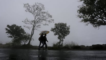 Unos j&oacute;venes se protegen de la lluvia este s&aacute;bado en Tegucigalpa (Honduras).
