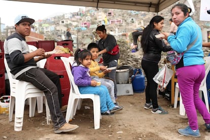 Grupo de pessoas come no cemitério de Nova Esperança, no populoso distrito de Vila Maria do Triunfo, em Lima (Peru).