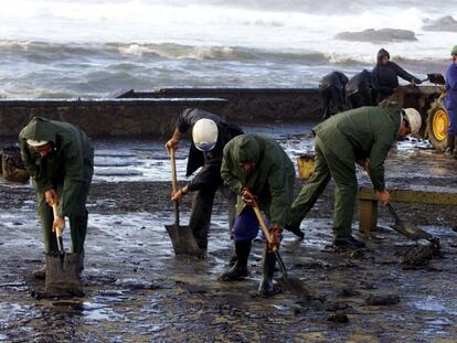 Trabajos de limpieza, con personal sin guantes, de la playa gallega de Muxía (A Coruña) contaminada por el fuel vertido por el accidentado petrolero 'Prestige'.