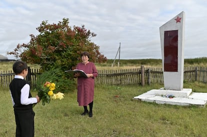 Ravil y su profesora Uminur Kuchukova, asisten a la ceremonia del primer día del nuevo año escolar junto a un monumento de la Segunda Guerra Mundial en el pueblo de Sibilyakovo.