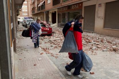 Unos vecinos sacan bolsas con ropa de un edificio en el barrio de San Diego (Lorca)