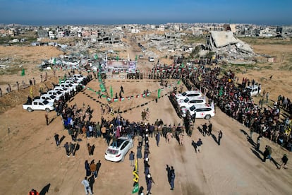 Vehículos de la Cruz Roja y palestinos esperan la entrega de los rehenes en Yan Junis, este sábado.