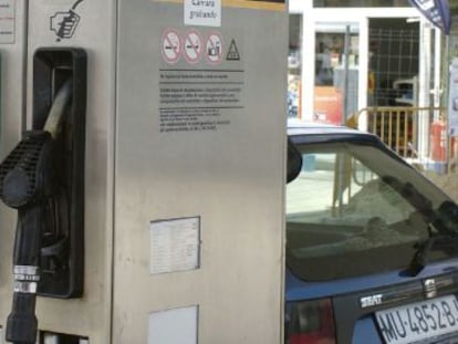 Un hombre pone gasolina a su coche en un surtidor. 