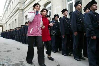 Dos mujeres pasan junto a una fila de estudiantes de la Armada que esperan para votar en un centro electoral de Bakú.
