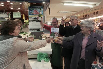 Los clientes de la pescadería en el mercado de Quintana celebran ganar parte del tercer premio de la lotería de Navidad, premiado con 500.000 euros por serie.