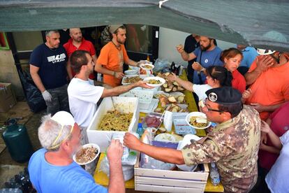 Trabajadores de los servicios de emergencia y víctimas del terremoto se alimentan gracias a una cocina improvisada.