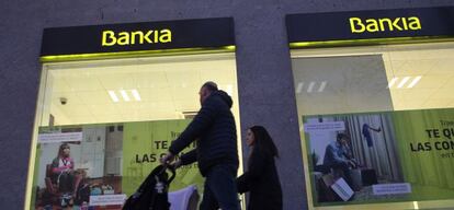 Una familia pasando por delante de una oficina de Bankia