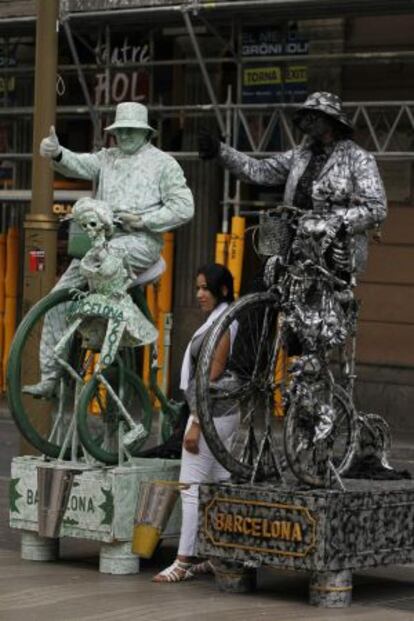 Una mujer se fotografía junto a dos estatuas humanas en la Rambla.