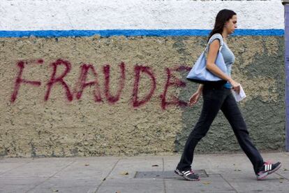 Una mujer camina frente a una pintada en Caracas.