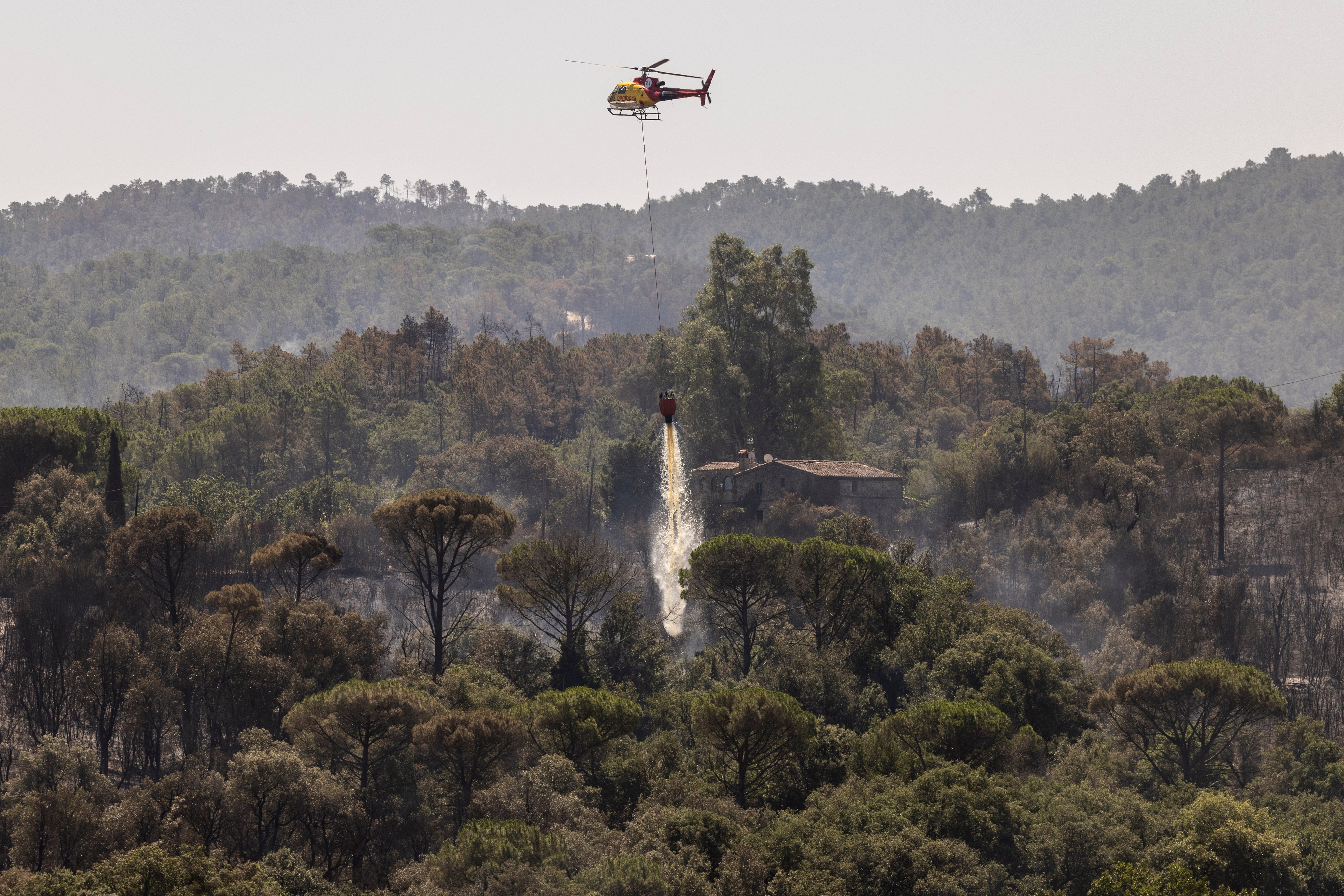 Un helicóptero lanza agua sobre la zona quemada Cruïlles, Monell i Sant Sadurní (Girona).