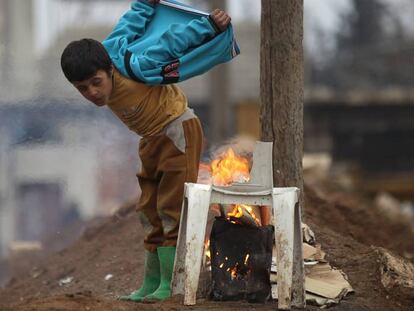 Un ni&ntilde;o se calienta, este jueves, con un fuego en la ciudad rebelde de al-Rai.