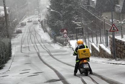 Un motorista intenta no caerse en una calle nevada en Manzanares El Real, Madrid.