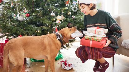 Una chica dándole un regalo de navidad a su perro.