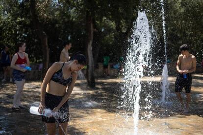 Un grupo de jovenes se refrescan en las fuentes de agua del parque del Tibidabo para hacer frente a la ola de calor.