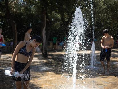 Un grupo de jovenes se refrescan en las fuentes de agua del parque del Tibidabo para hacer frente a la ola de calor.