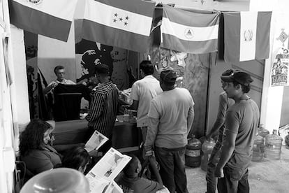 Una voluntaria entrega ropa a un grupo de inmigrantes. Al fondo, las banderas de El Salvador, Honduras, Nicaragua y Guatemala.