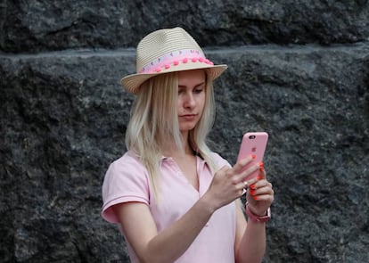 A journalist uses her iPhone as she waits for a news conference in front of the Presidential Administration headquarters in Kiev