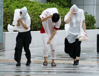 Três pedestres lutam contra as fortes rajadas de vento provocadas pelo tufão Jebi, em Nagoya (Japão).