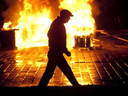 Un hombre pasa una barricada de fuego hoy en Bucarest (Ruman&iacute;a).