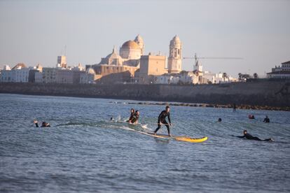 Varios deportistas practican surf en la playa de Santa María del Mar de Cádiz. Desde este sábado, las personas mayores de 14 años pueden ir a pasear y hacer deporte individual, respetando unos horarios y la distancia de seguridad, unas salidas que se suman a los paseos de los niños que comenzaron a estar permitidos el pasado domingo tras semanas de confinamiento por el coronavirus.