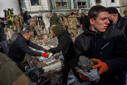 Equipos de rescate y residentes retiran los escombros del edificio residencial atacado por un bombardero ruso en Uman.