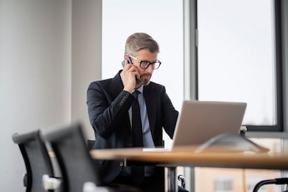 Professional businesman using cellphone and laptop at work