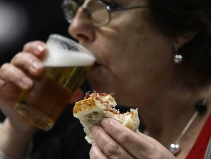 Una consumidora con una cerveza y una tapa en un bar de Madrid.