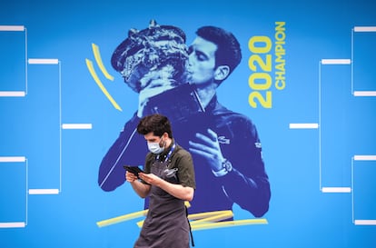 Un trabajador de Melbourne Park, ante una imagen de Djokovic.