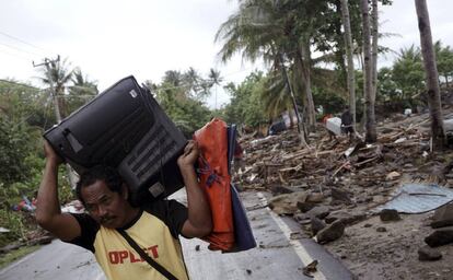 Um homem salva sua televisão depois que um tsunami sacudiu Anyer.