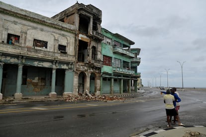 Una pareja observa un edificio dañado por la lluvia y los fuertes vientos.